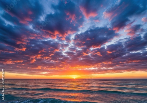 Vibrant sunset over a calm ocean with dramatic clouds and fiery hues