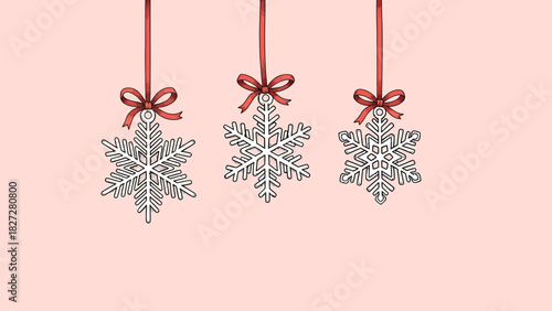 Three hanging snowflake ornaments with red ribbons and bows against a soft pink background.