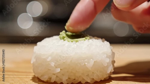 Sushi preparation technique adding wasabi restaurant kitchen culinary art contemporary setting close-up view food presentation