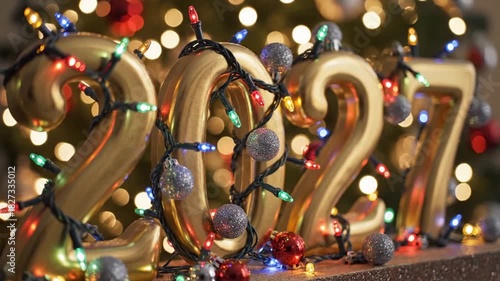 Golden New Year 2027 balloons and festive holiday lights create a celebratory atmosphere