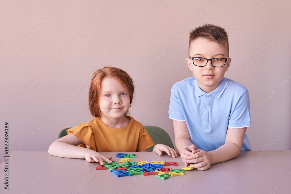 Fototapeta premium Caucasian children playing with colorful alphabet letters on table.