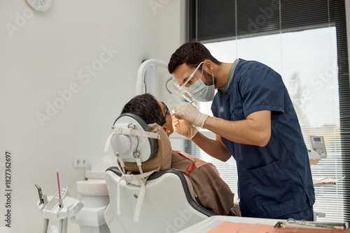 Foto Young adult male dentist examining mature Caucasian woman sitting in dental chai