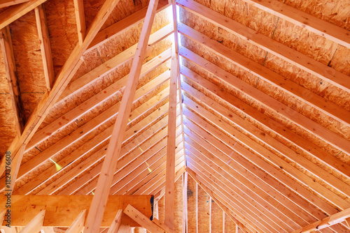 Roof structure wooden beams with streaming in, providing an open, spacious feel at building site.