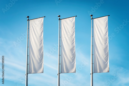 Three vertical white flags waving against a clear blue sky