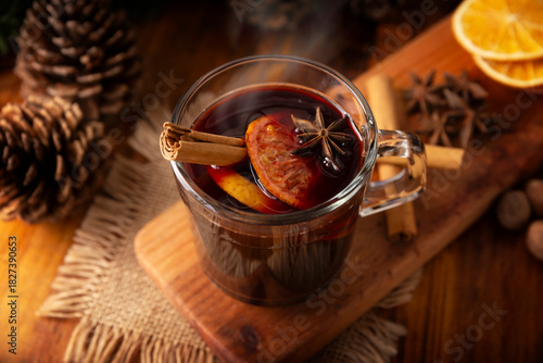 Hot wine or Christmas mulled wine with orange, cinnamon, star anise, clove, nutmeg and other ingredients on a wooden rustic table. Traditional hot drink at winter time and Christmas holidays.
