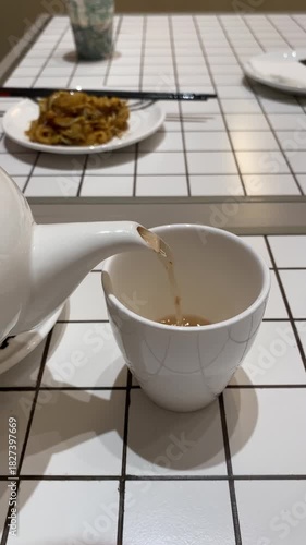 4k vertical video footage of A woman is pouring hot tea from a teapot into a teacup
