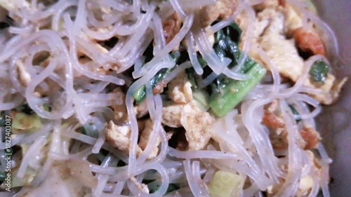 Delicious fried vermicelli are a popular Indonesian dish with shrimp, egg, and vegetables. Served in a white styrofoam container. Food videography.