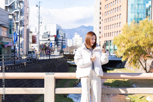 橋の上でスマホを操作する女性