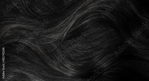 Brunette or black hair. Female long dark hair in black. Beautifully laid curls. Closeup texture in a dark key. Hairdressing, hair care and coloring. Shading gray hair. Background with copy space.