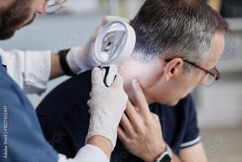Obraz na płótnie Middle aged Caucasian man sitting while male dermatologist examining scalp with