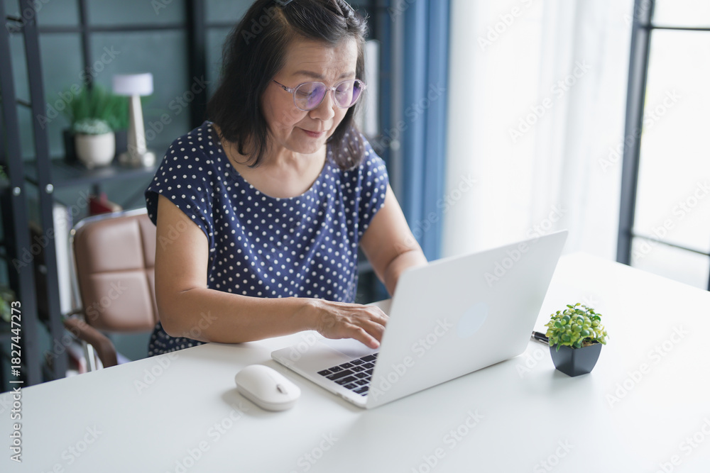 Fototapeta premium Mature Asian woman Work from home. senior&nbsp;asian woman on laptop with technology concept.