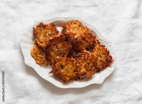 Crispy latkes potatoes on a white plate on a light background, top view