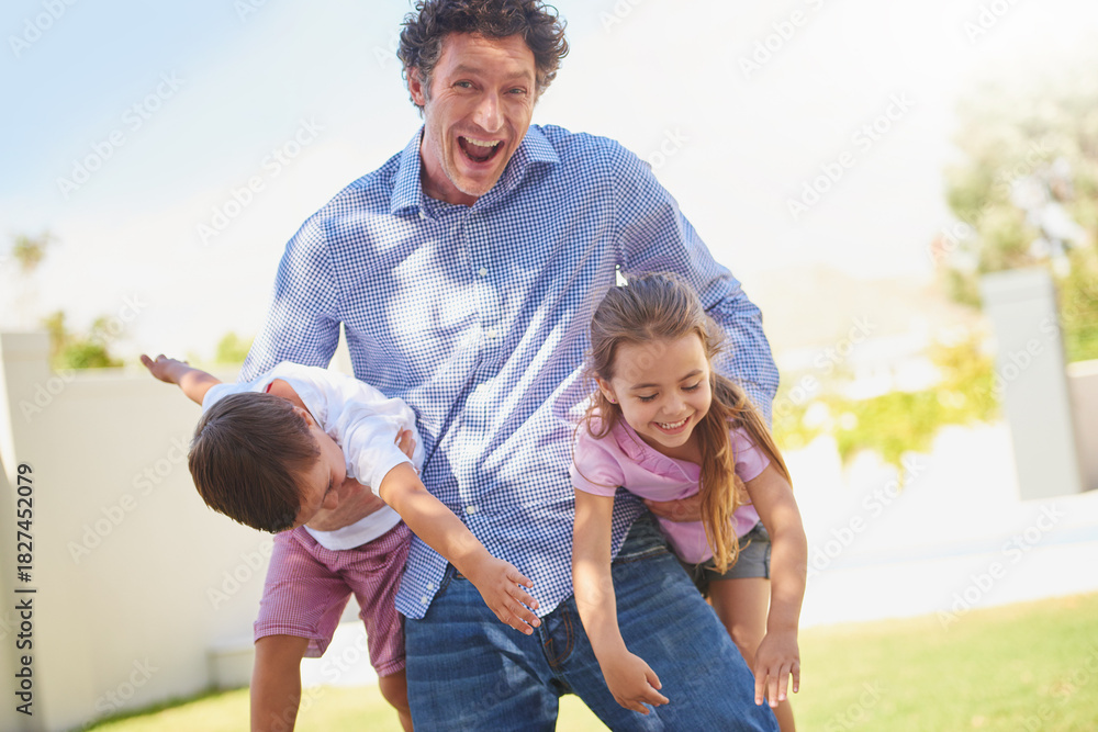Fototapeta premium Father, playful and carry children in backyard, portrait and excited for games, love or care in summer. Man, dad and kids with joke, laugh and fun for bonding on lawn at family house in New Zealand