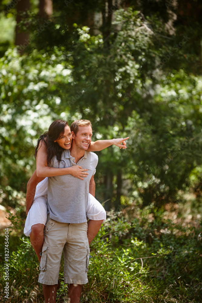 Obraz premium Pointing, piggyback and couple in park for vacation, love and laugh together with partner. Funny, man and carry woman outdoor for holiday adventure, support and explore nature for sightseeing