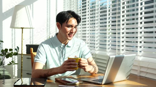 Lifestyle people, Man using laptop computer and smartphone and enjoys a coffee. Happy man, entrepreneur, small business owner working online at home office.