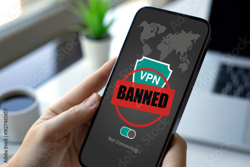 Female hands holding phone with VPN banned on screen laptop