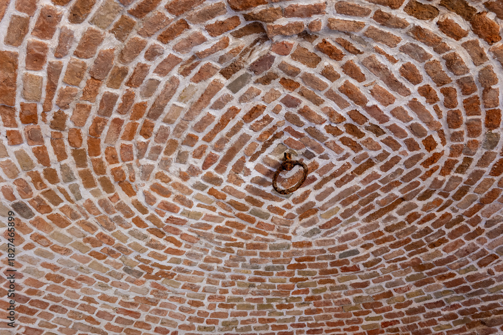Fototapeta premium Brick vaulted ceiling of a historical ice pit in Bratislava, showing circular brick pattern and old metal ring detail.