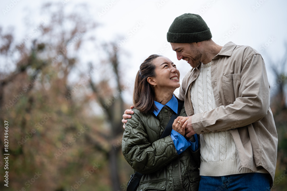 Fototapeta premium Diverse couple smiling, holding hands enjoying autumn walk