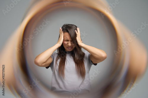 Conceptual image of woman with headache surrounded by blurred tunnel effect