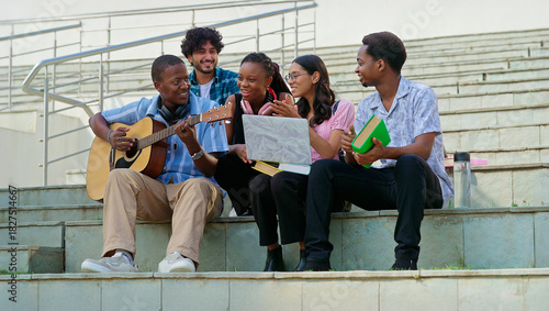 Foto Indian young adult gen z lady woman male man group sitting on stair hold guitar play music sing song have fun joy