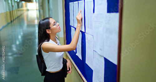 Fotografie Indian young adult gen z busy pupil girl look notice board check study exam resu