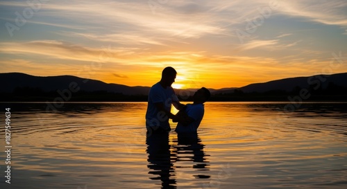 Baptismal immersion rite performed at sunset in a tranquil lake environment
