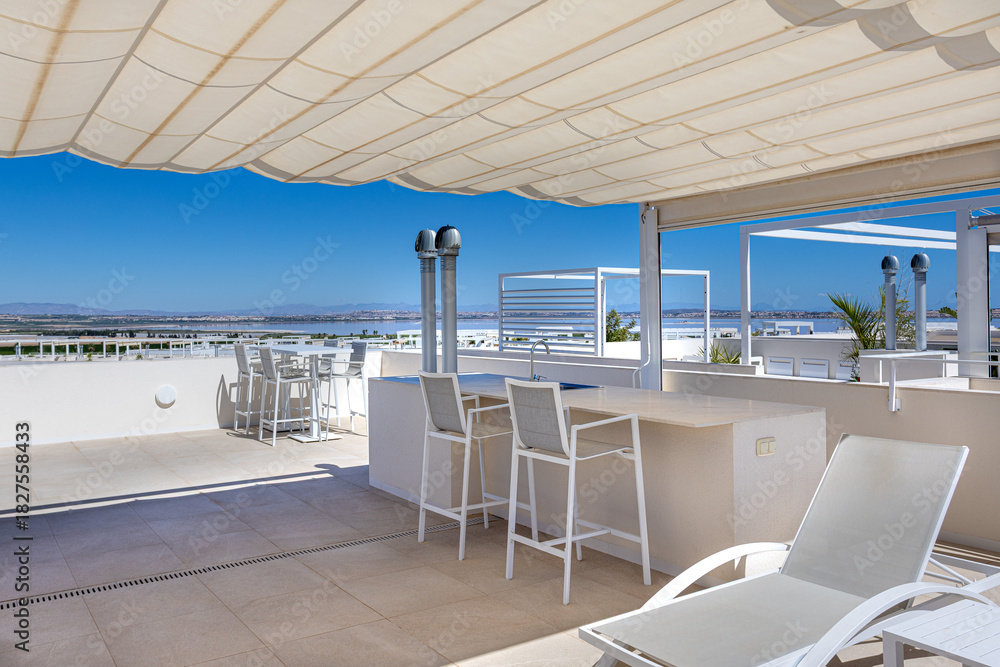 Fototapeta premium Rooftop terrace with sea view, bar seating, and sun loungers under canopy