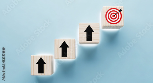 Ascending wooden blocks with upward arrows lead to a bullseye target, symbolizing strategic business growth and successful goal achievement.