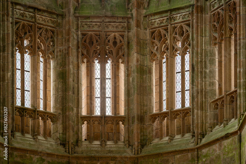 Detailed view of the Gothic window architecture and stone carvings in the church of Mont Saint-Michel. Gothic stained-glass windows and intricate stone tracery inside Mont Saint-Michel Abbey, France. 