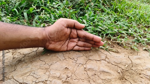 Environmentalist or conservationist hand protecting wet green grass earth fertile ground soil from cracked dry infertile land. Stop desertification, save nature and climate change prevention concept.