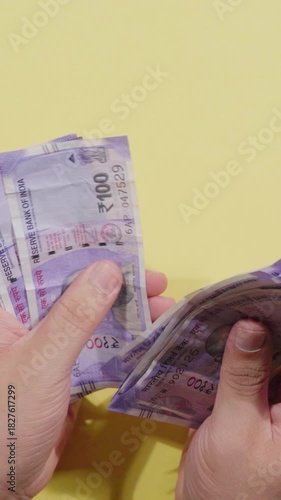 Vertical Video of Man Counting One Hundred (100) Indian Rupees Notes