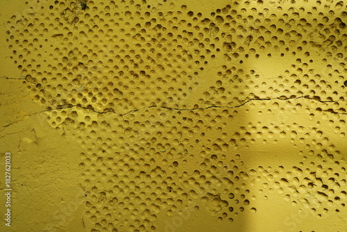 Mur ancien avec alvéoles rondes peint en jaune.