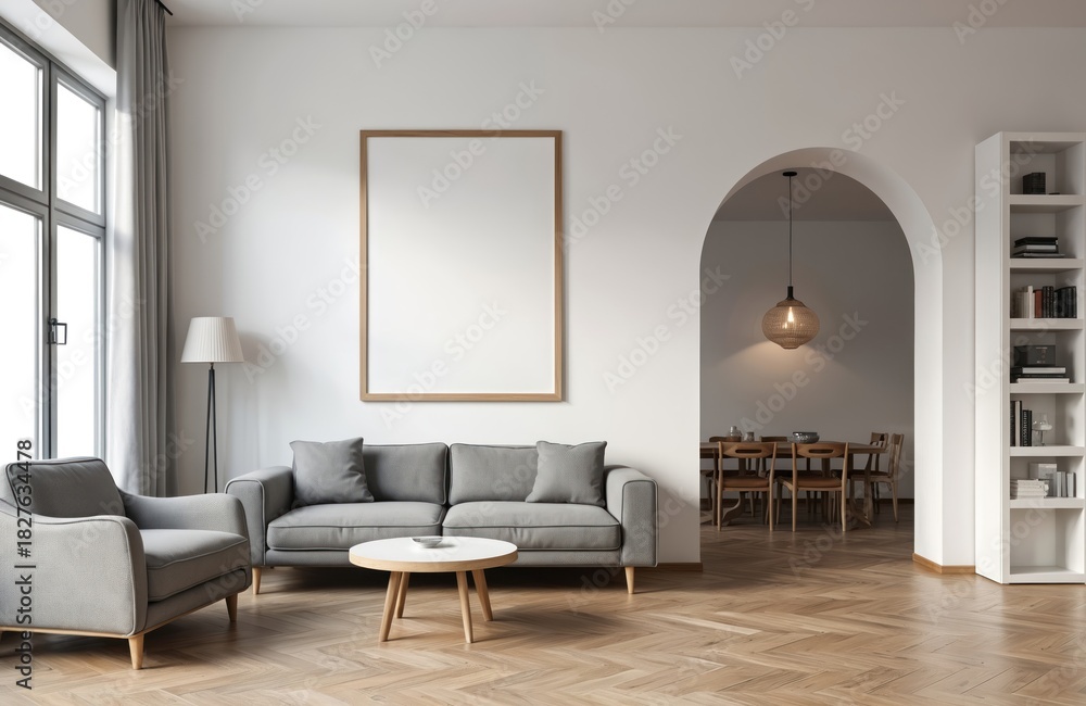 Fototapeta premium Modern living room with gray sofa and armchair. Empty frame above couch. Archway to dining area with table and chairs. Bookshelf with decor. Bright natural light from large window.