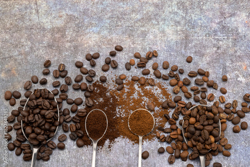 Different of roasted coffee beans with spoons on old texture rusty background