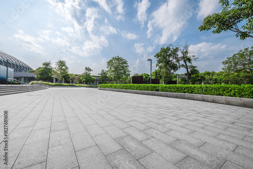Empty square floor and modern building with green plants.