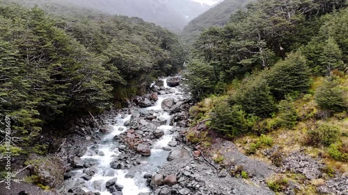 Low flying over a beautiful mountain river in the rain in New Zealand. Natural landscape. 
