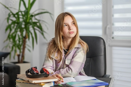 Thoughtful teenage girl studying at desk