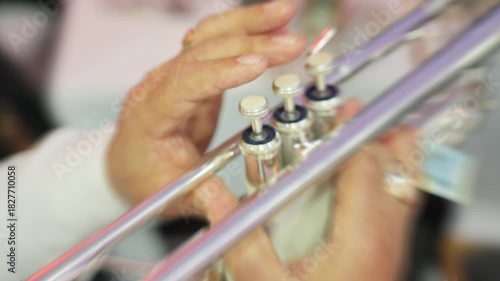03. 10. 2025 munich. germany. closeup hands on trumpet valves highlighting seasoned musician shaping bright tones under stage lights with polished brass reflections, precise finger motion and lively