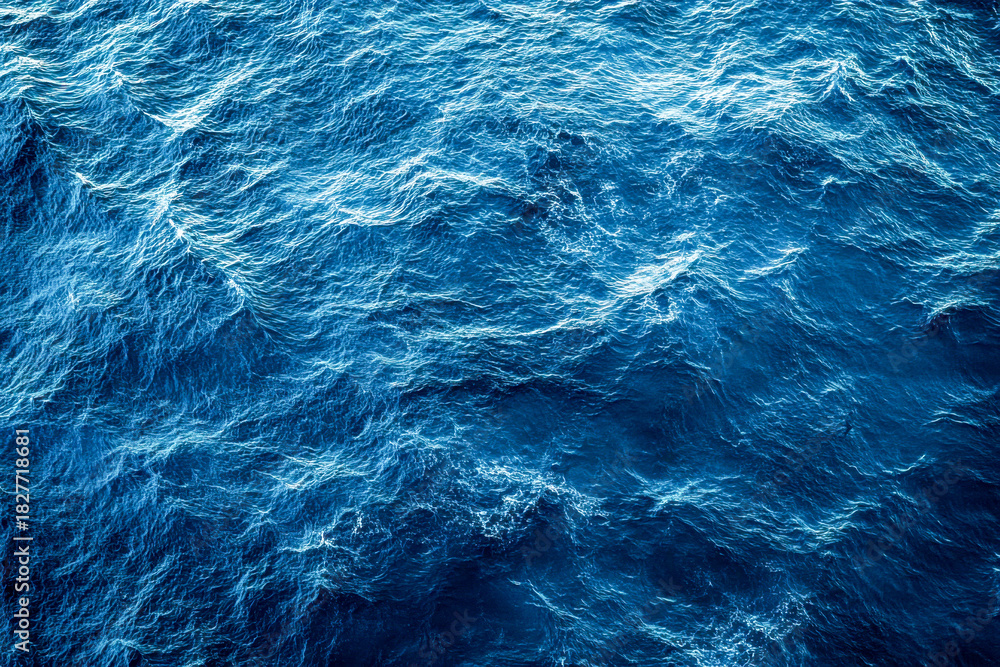 Fototapeta premium Sunlight reflects off the ocean surface, creating a vibrant display of deep blue waves rolling gently throughout the water