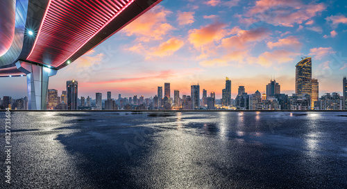 Empty wet asphalt road and modern city commercial buildings with skyline at sunset in Shanghai