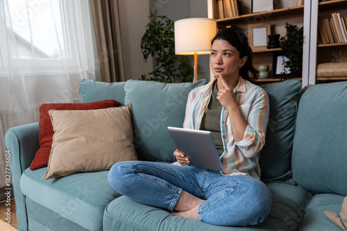 Young woman relaxing at home browsing digital tablet to compare online shopping options track delivery update explore food order service and choose new clothing items through modern ecommerce platform
