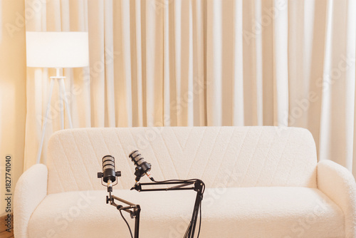 Podcast setup with microphones and cozy seating in modern studio space