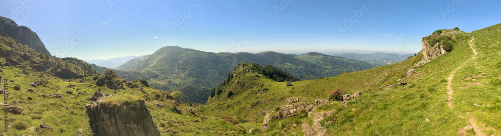 Fototapeta premium Panoramic view of lush green mountain hills under a clear blue sky