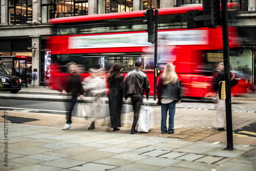 Foto Iconic red double-decker buses speeding past blurred shoppers on Regent Street,