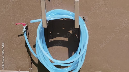 The faucet attached to the hose has a ring fixed to the wall.