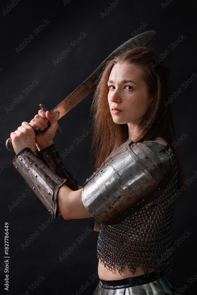 Obraz premium Portrait of a young woman, fantasy warrior in armor with a sword in her hands isolated on a dark background.