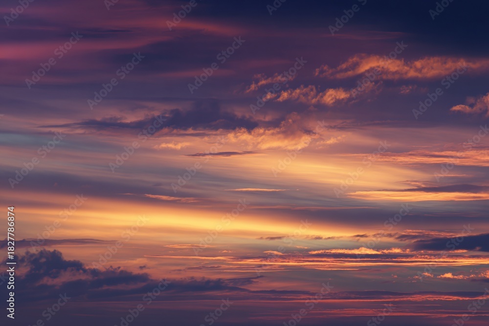 Obraz premium Dramatic Sunset Sky - Swirling Clouds Painted with Vibrant Orange and Purple Hues.