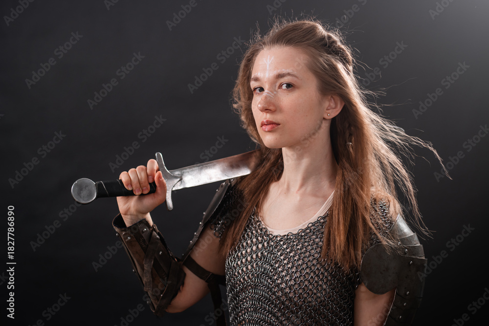 Obraz premium Portrait of a young woman, fantasy warrior in armor with a sword in her hands isolated on a dark background.