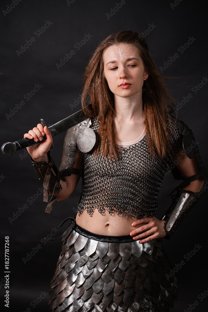 Obraz premium Portrait of a young woman, fantasy warrior in armor with a sword in her hands isolated on a dark background.