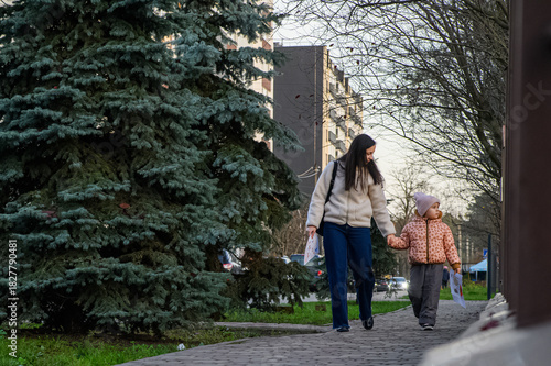 Mother Walking with Child in Urban Neighborhood Holding Drawings